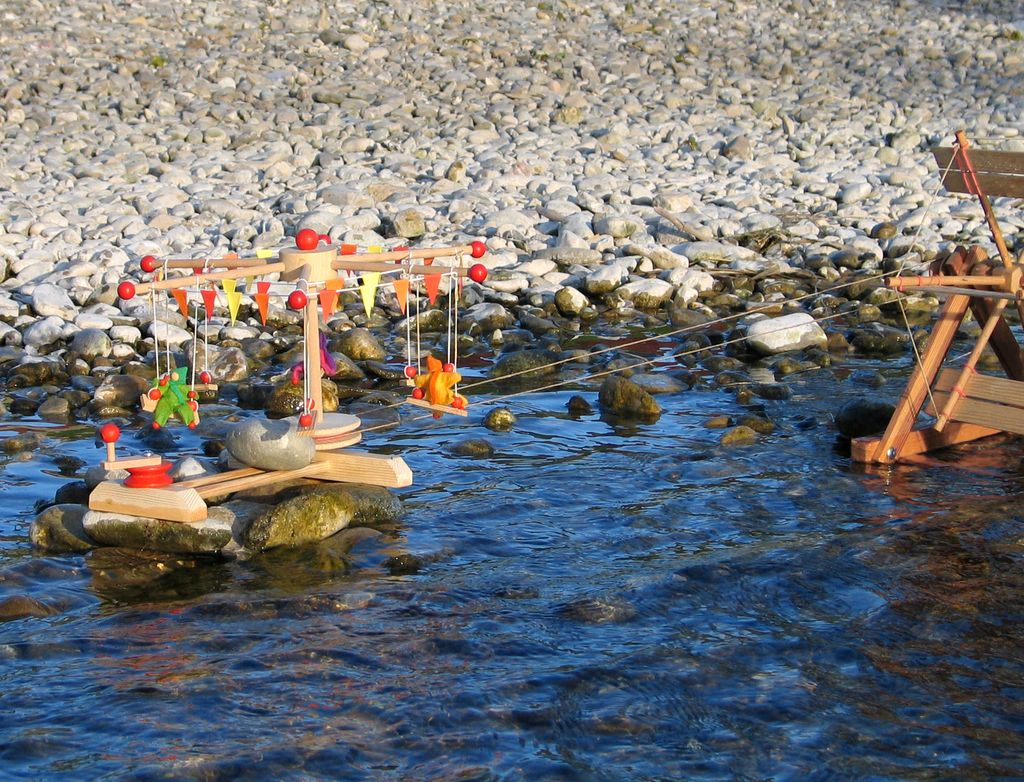 Kettenkarussell am Bach – mit Wasserrad angetrieben, bunte Püppchen auf Schaukeln