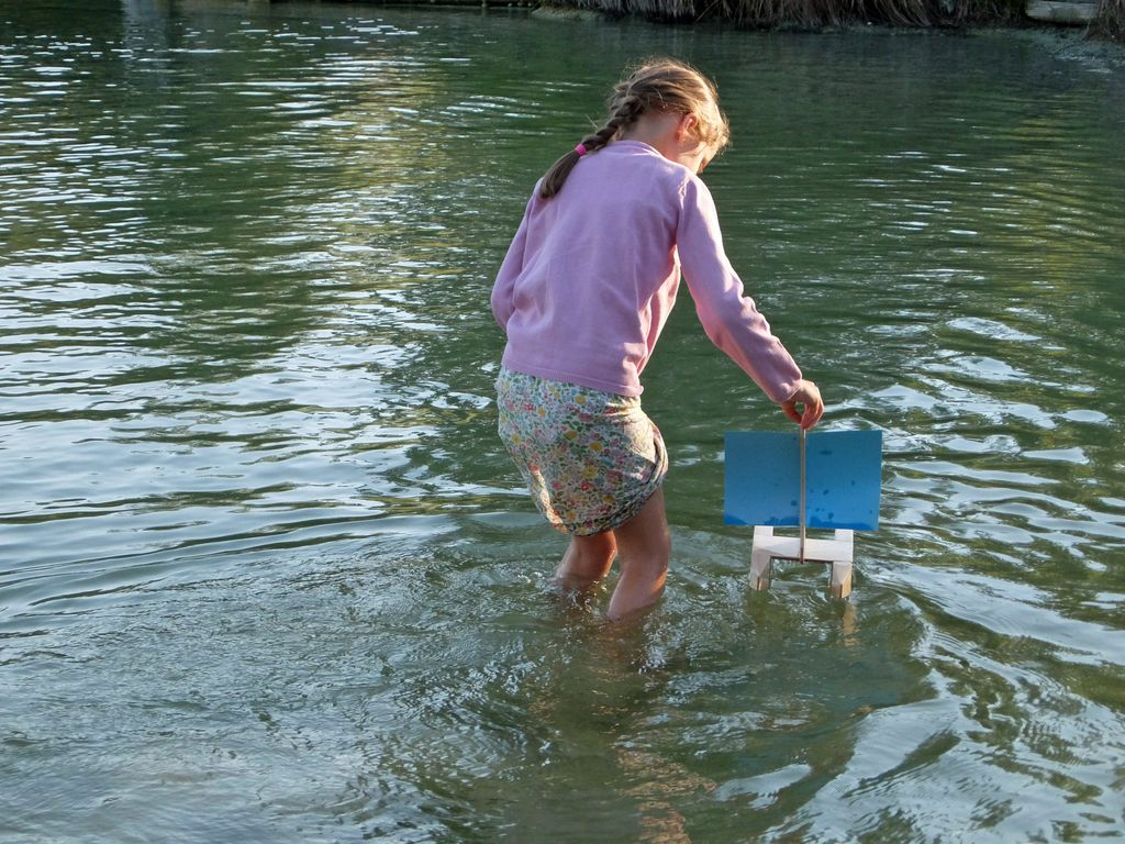 Mädchen spielt mit Kári Segelboot im Wasser
